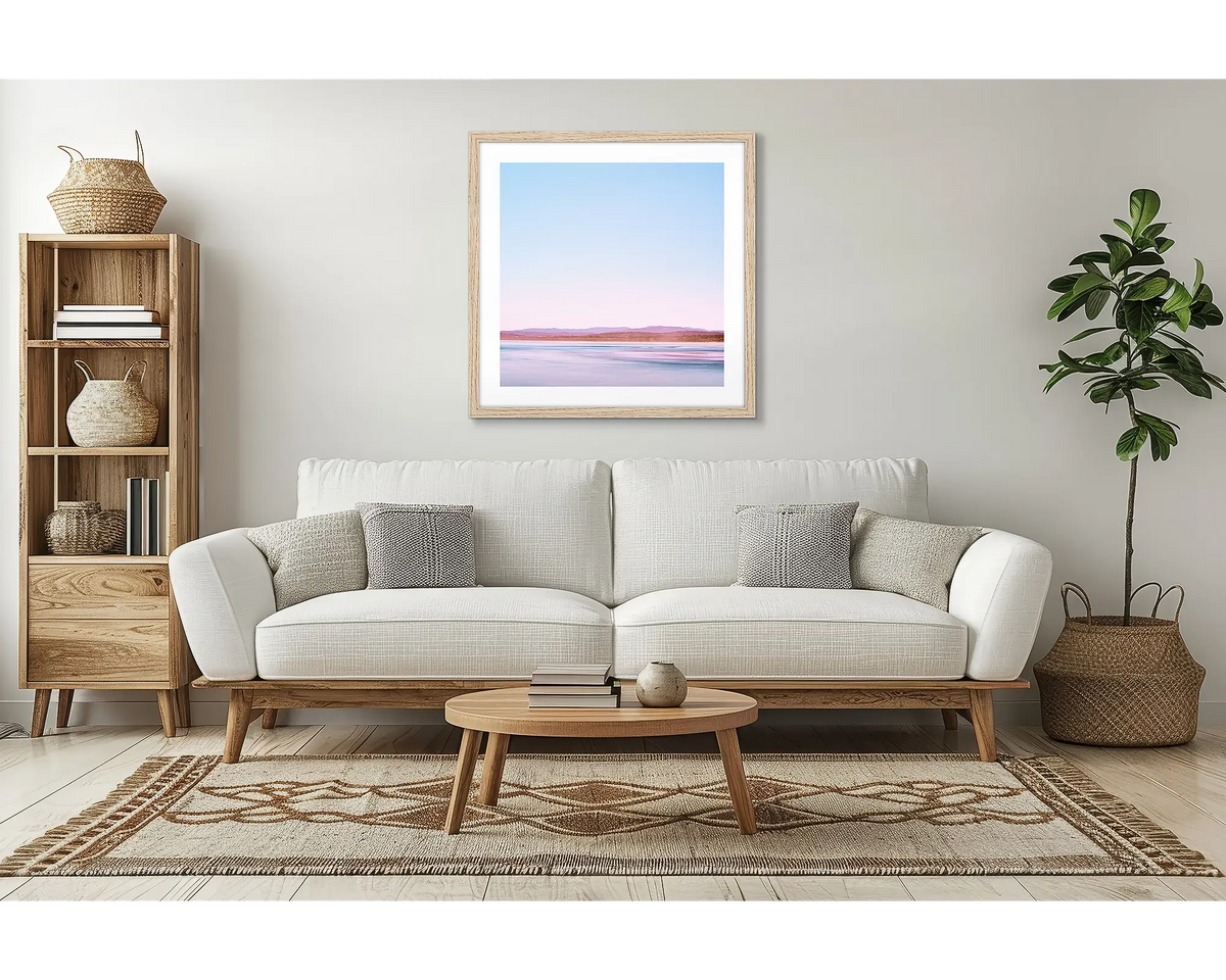 Perspective. Coastal wall art with a timber frame, in a lounge room, above a couch. 