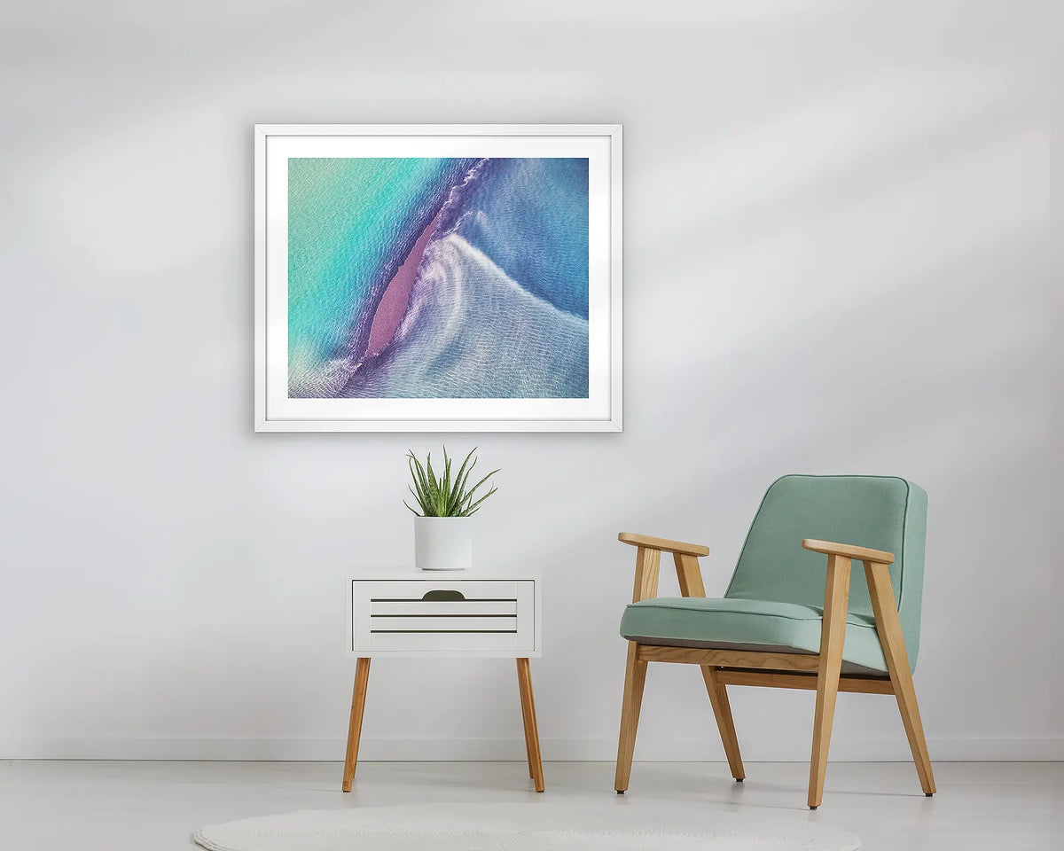 Recline. Abstract Kimberly artwork, in a white frame, above a small table.