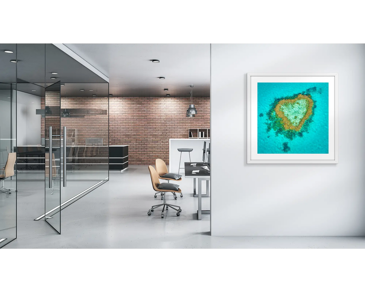 Reef Romance. Heart reef, Great Barrier reef wall art print with a white frame, in a modern office. 