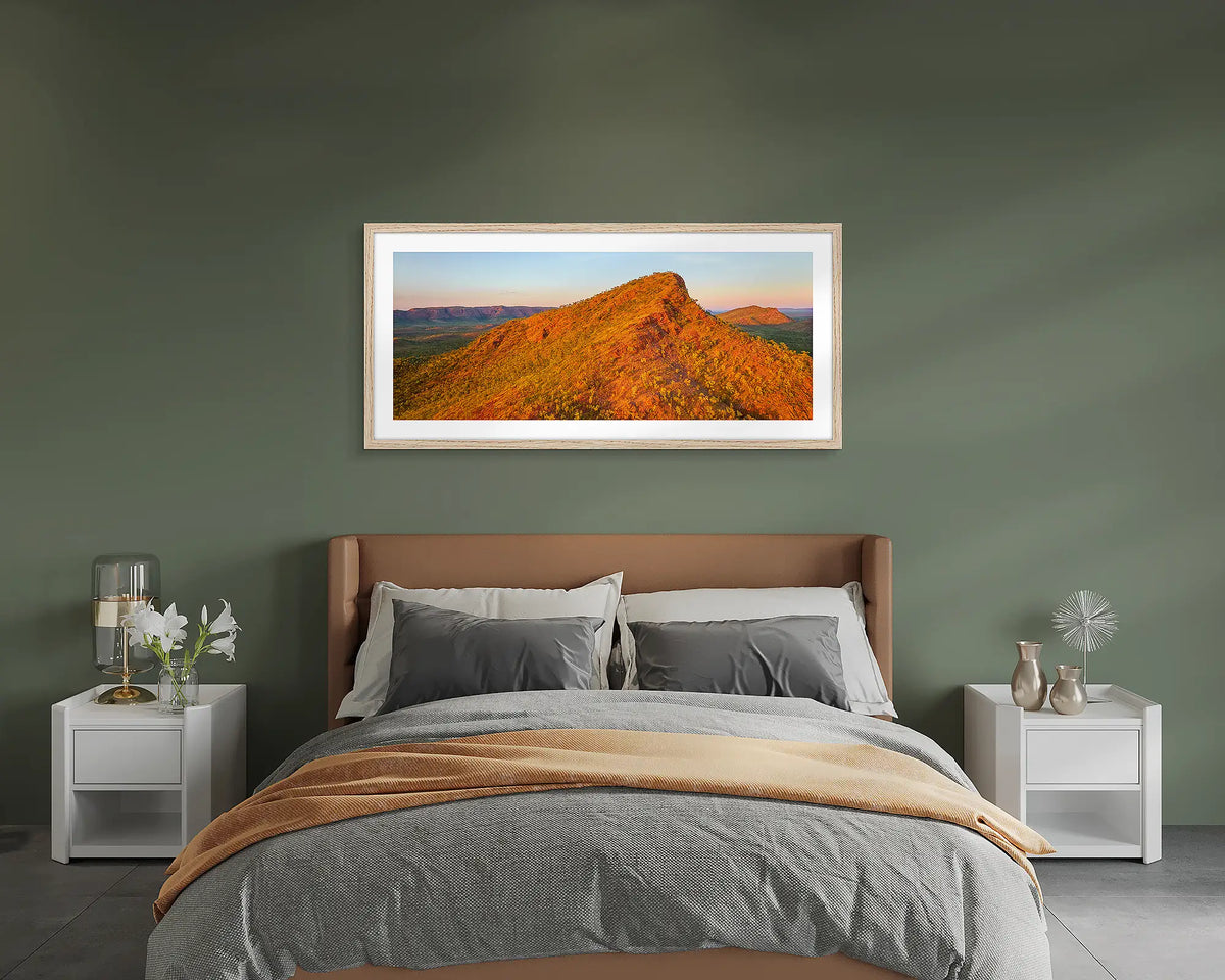 Rise. Wall art print of a Kimberley sunrise, with a timber frame, above a bed.