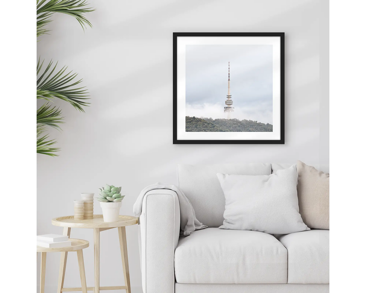 Rising. Framed Black Mountain Tower wall art print, with a black frame, hung above a couch.