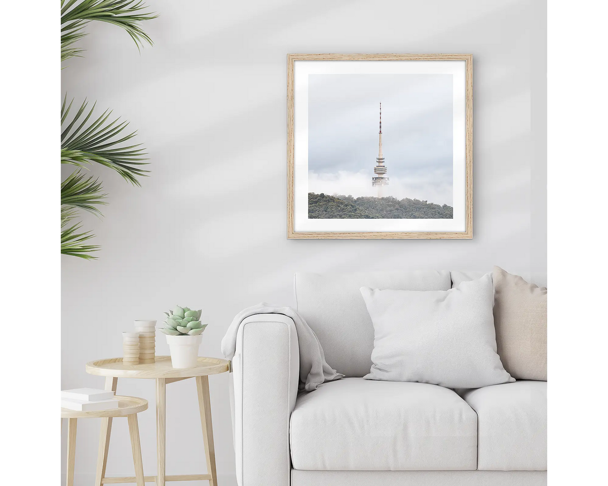 Rising. Framed Black Mountain Tower, wall art print with a timber frame, hung above a couch.