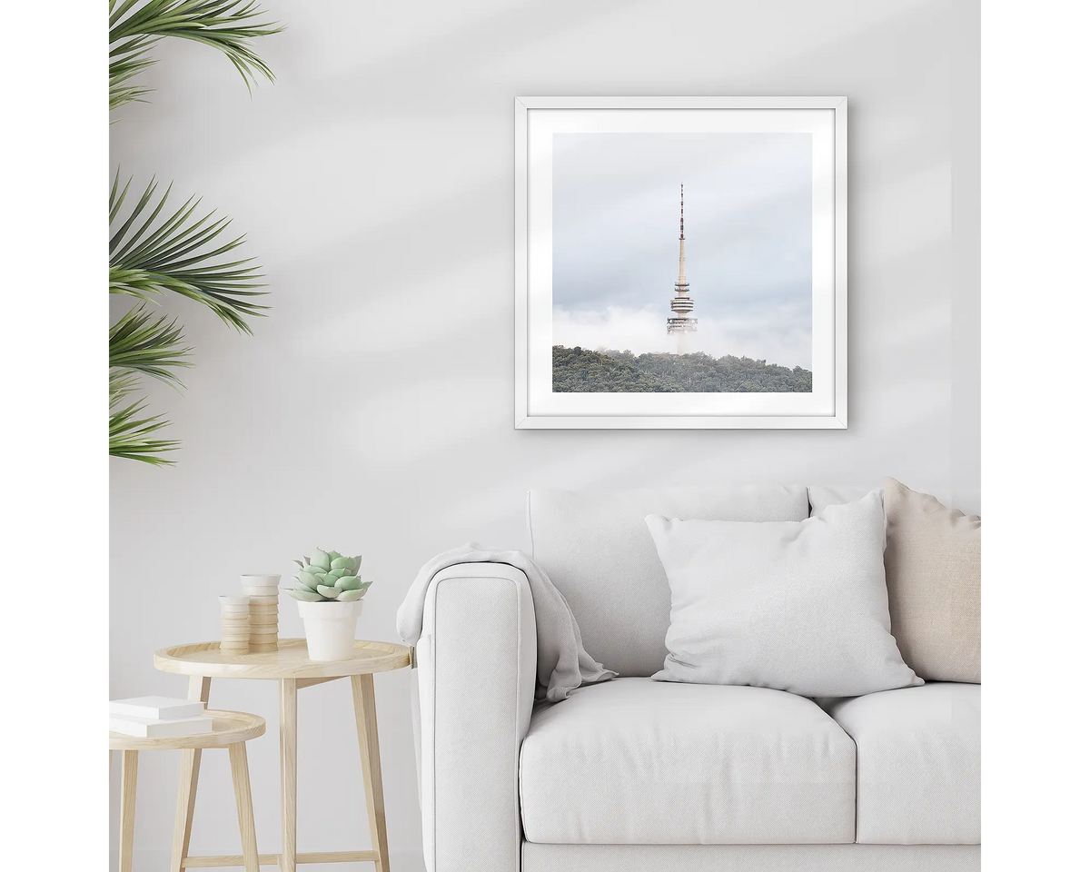 Rising. Framed Black Mountain Tower, wall art print with a white frame, hung above a couch.