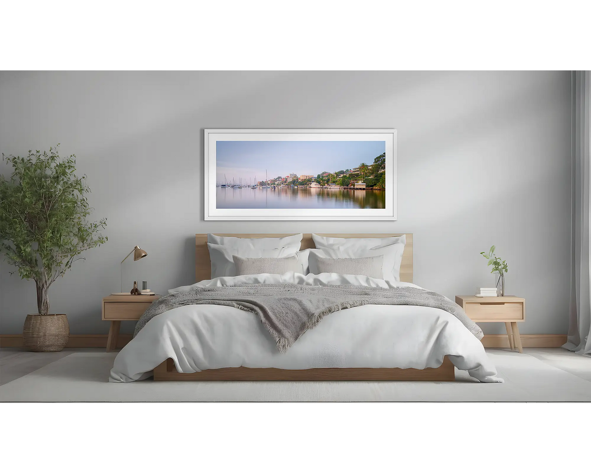 Seclusion. Sydney Harbour wall art with a white frame, above a bed. 