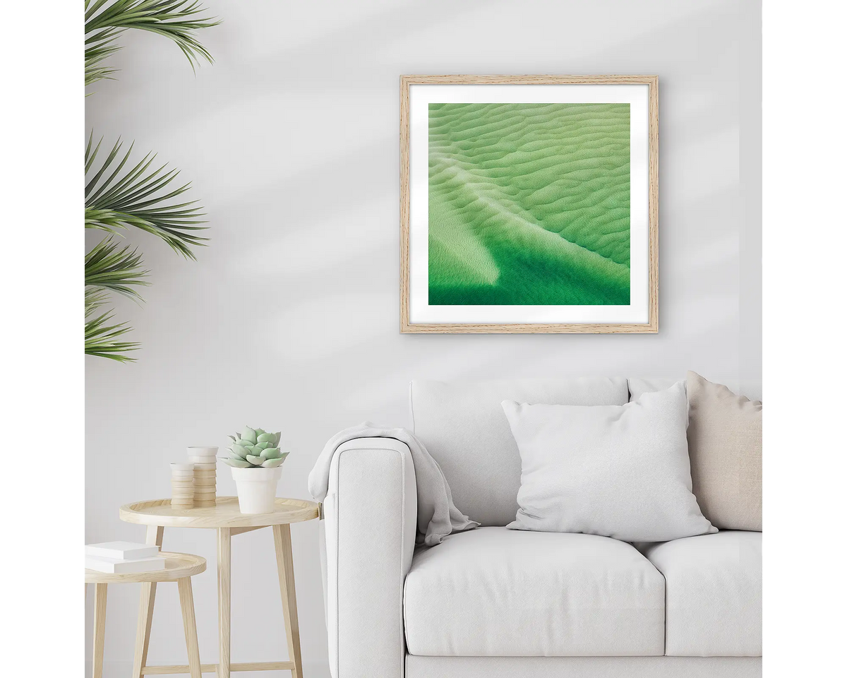 Shallows. Framed Whitsunday wall art print, with a timber frame, hung above a couch.