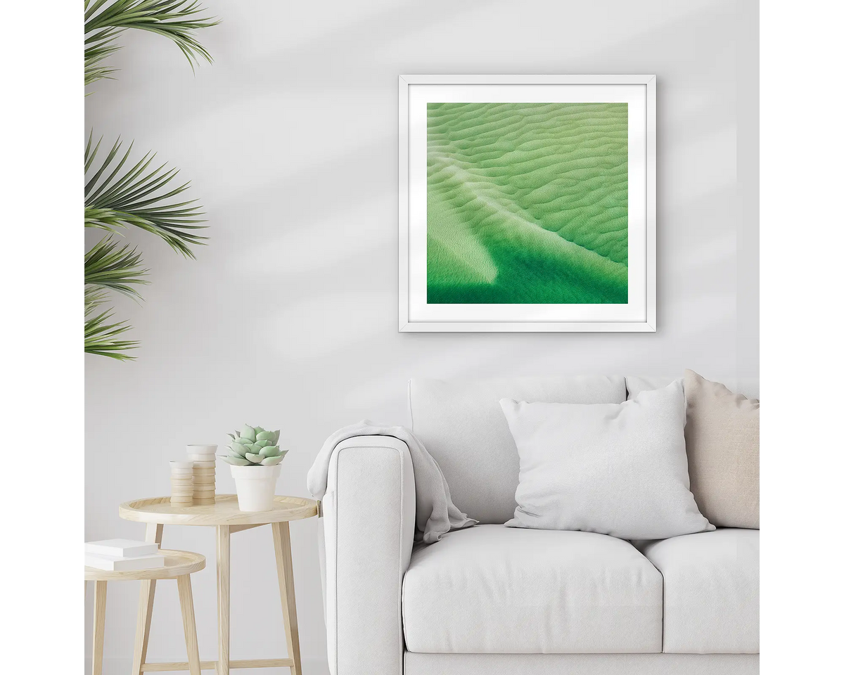 Shallows. Framed Whitsunday wall art print, with a white frame, hung above a couch.