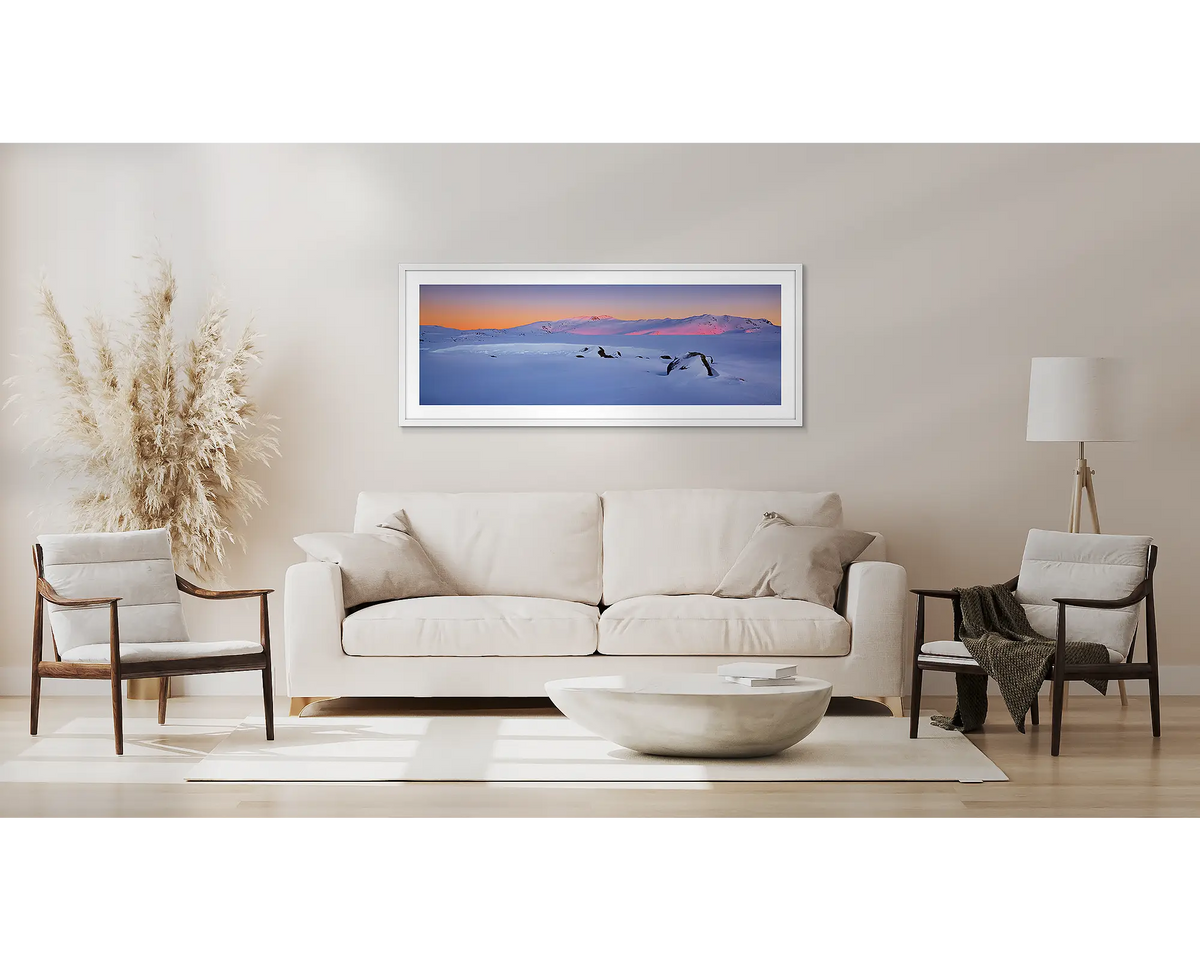 Snowy Sunrise. Kosciuszko National Park wall art print, framed with a white frame and hung above a lounge. 