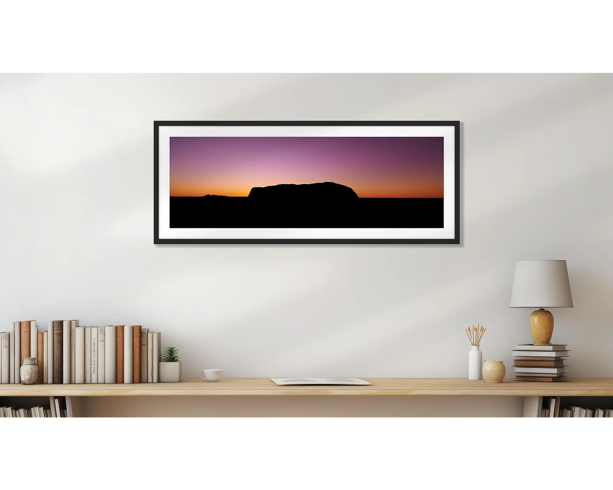 Spiritual Heart. Uluru framed wall art print, with a black frame, hung above a bookshelf. 