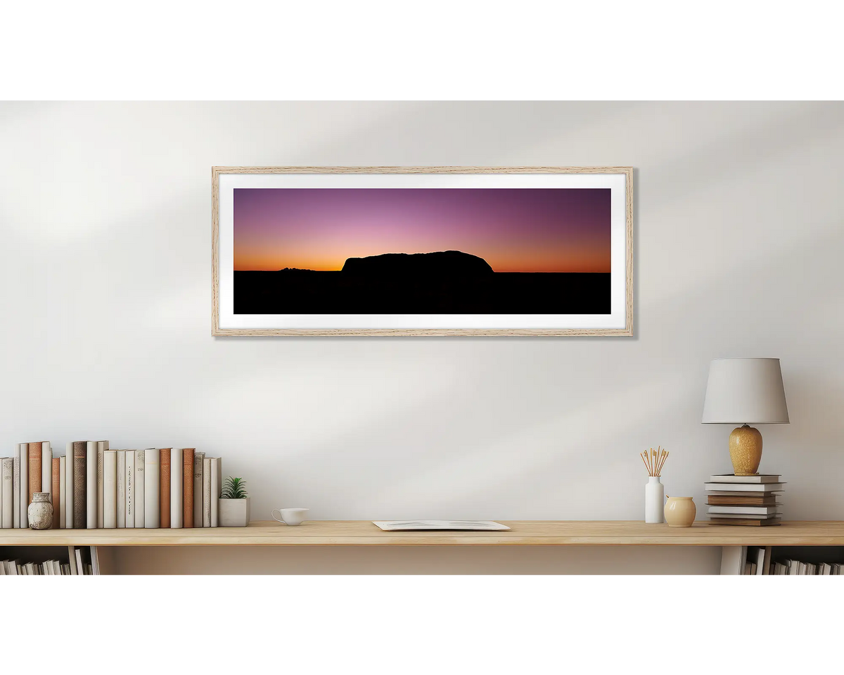 Spiritual Heart. Uluru framed wall art print, with a timber frame, hung above a bookshelf. 