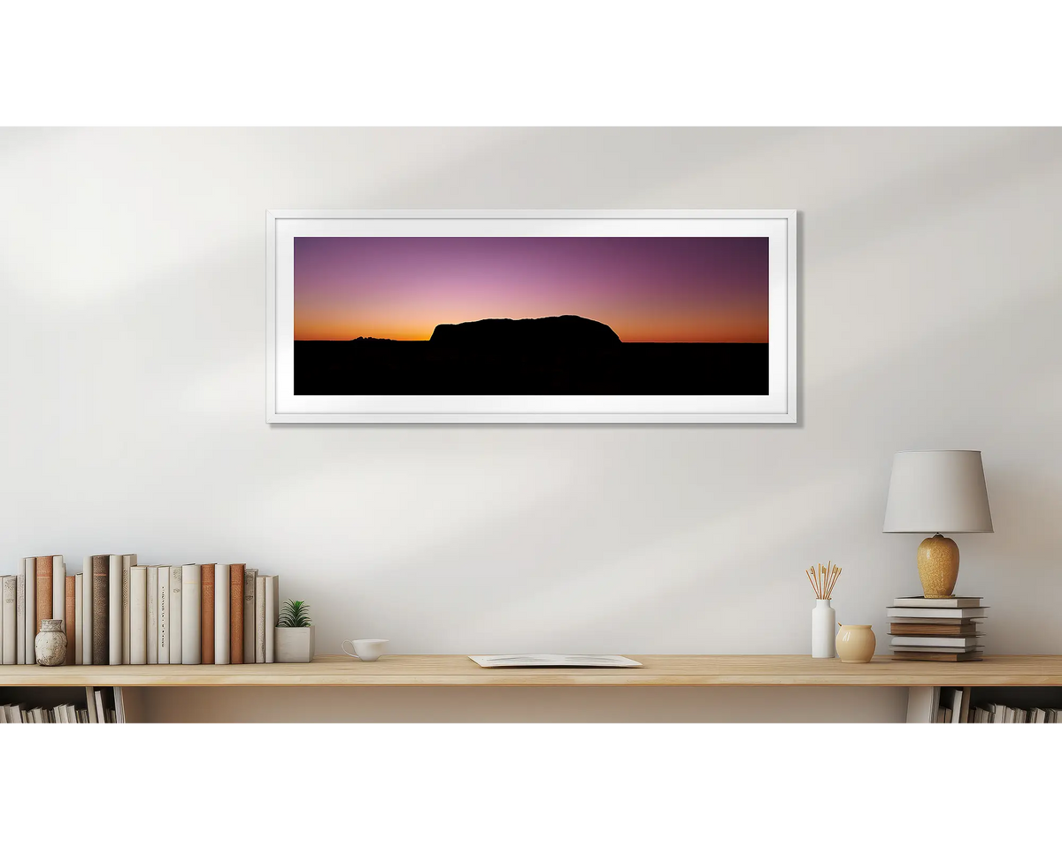 Spiritual Heart. Uluru framed wall art print, with a white frame, hung above a bookshelf. 