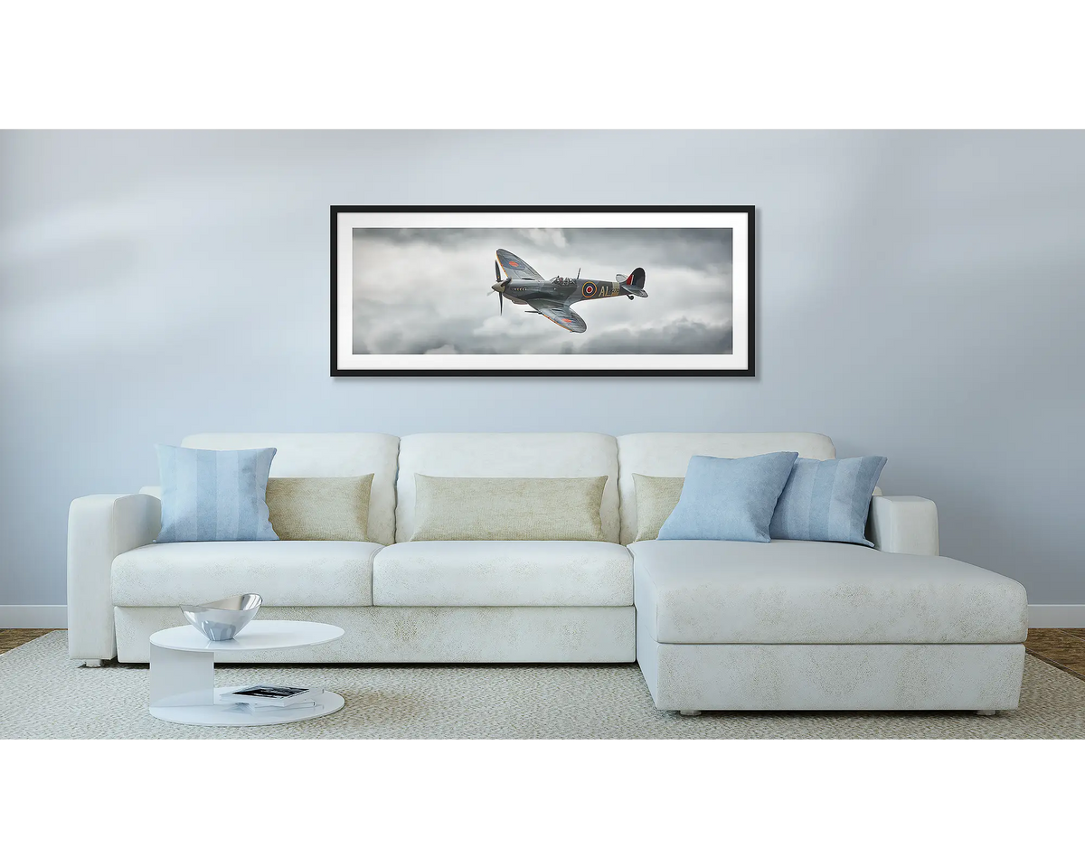 Spitfire. Aviation wall art, with a black frame, hung above a couch.