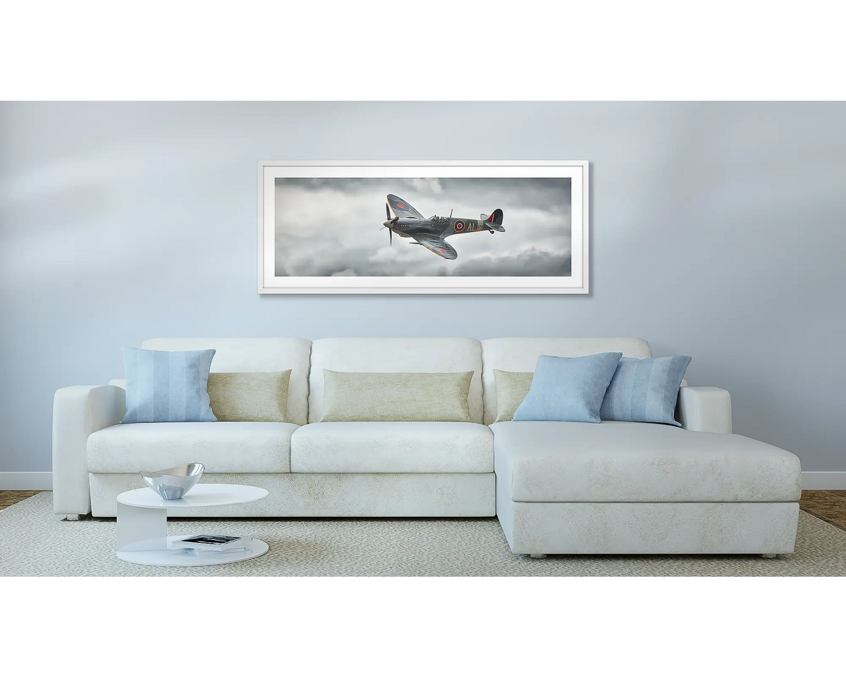 Spitfire. Aviation wall art, with a white frame, hung above a couch.