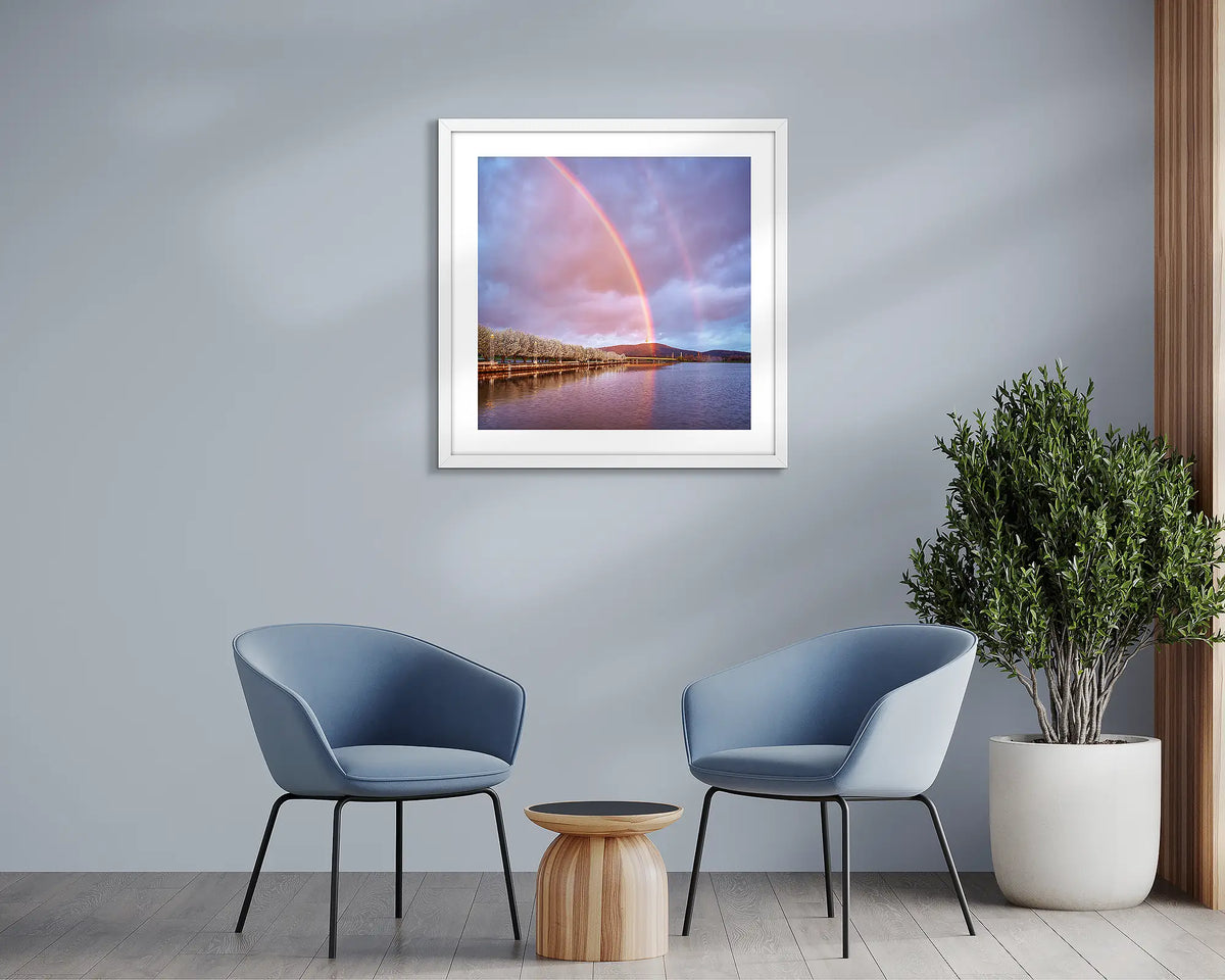 Spring Delight. Canberra rainbow wall art print, framed with a white frame and hung above two chairs. 