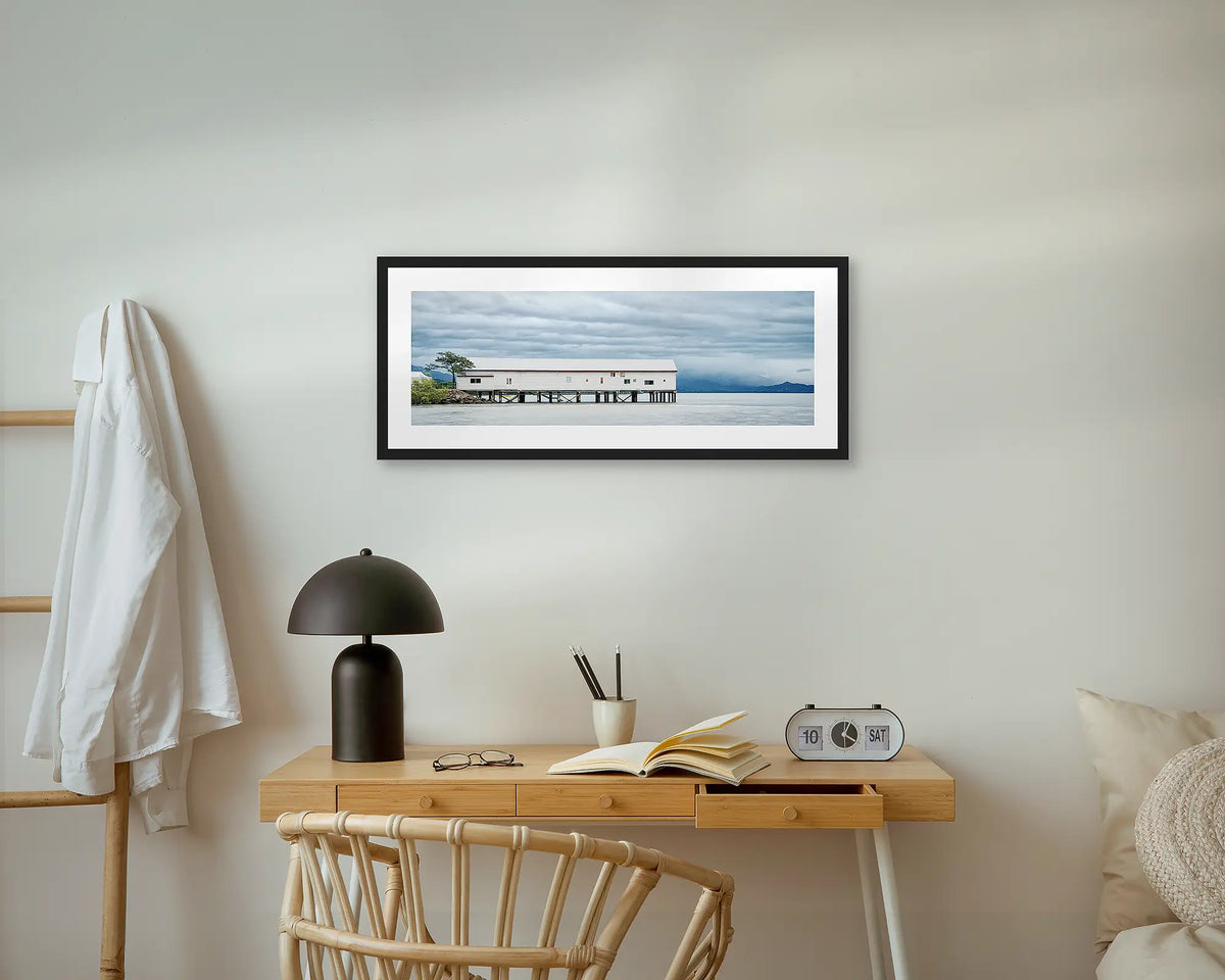 Sugar Wharf. Port Douglas wall art print, with a black frame, above a small desk.