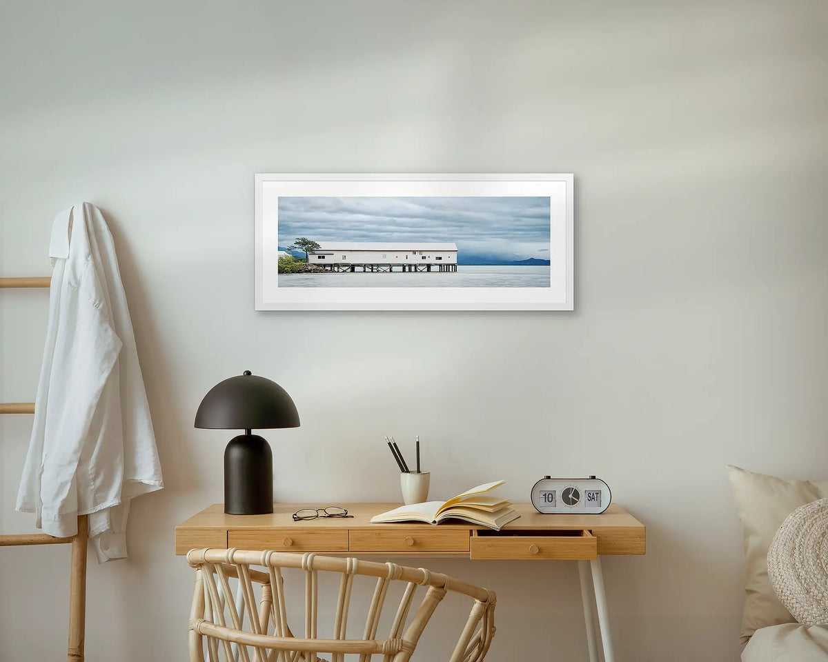 Sugar Wharf. Port Douglas wall art print, with a white frame, above a small desk.