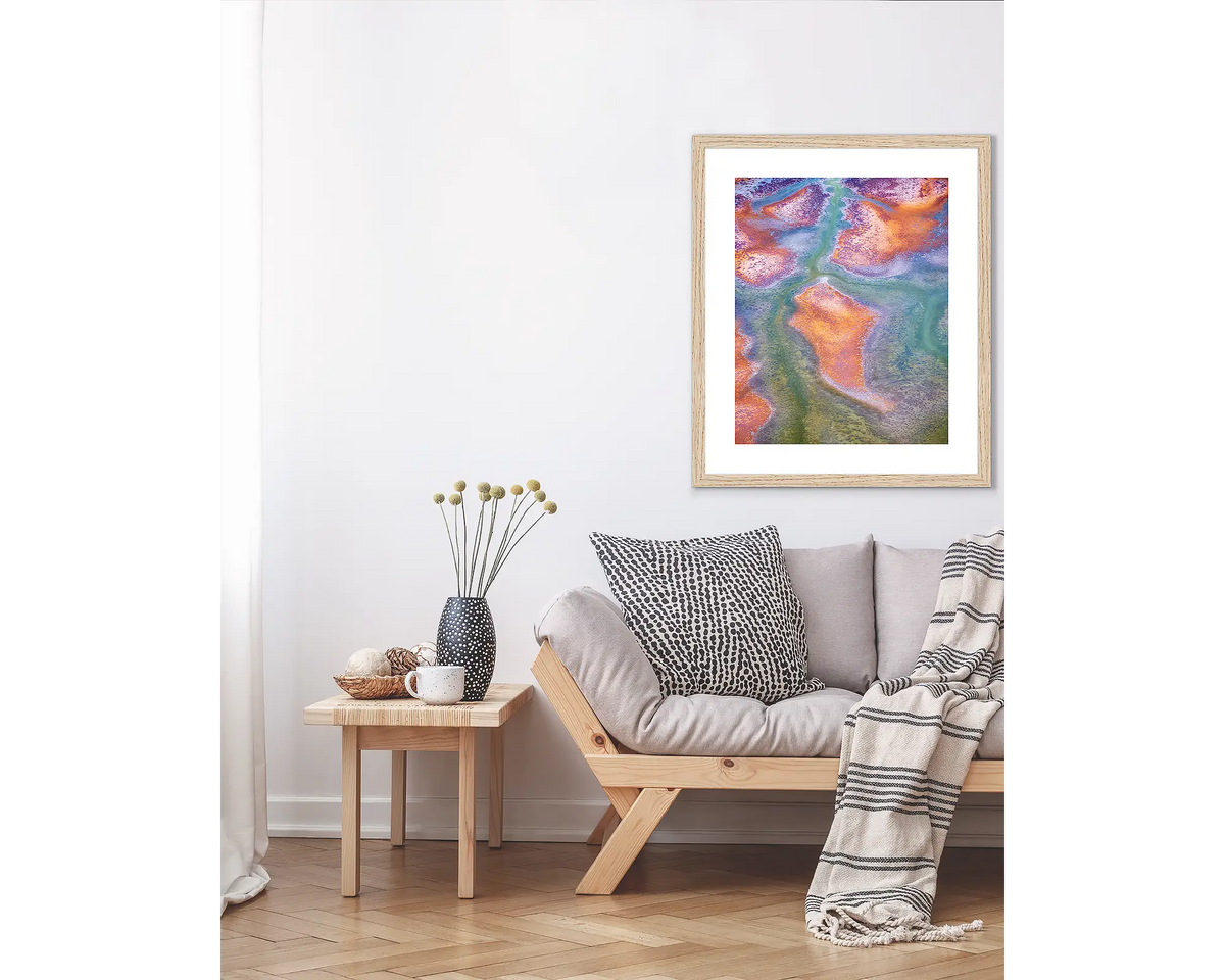 Surface. Abstract Kimberley wall art print, in a Tasmanian Oak frame, hanging above a couch.