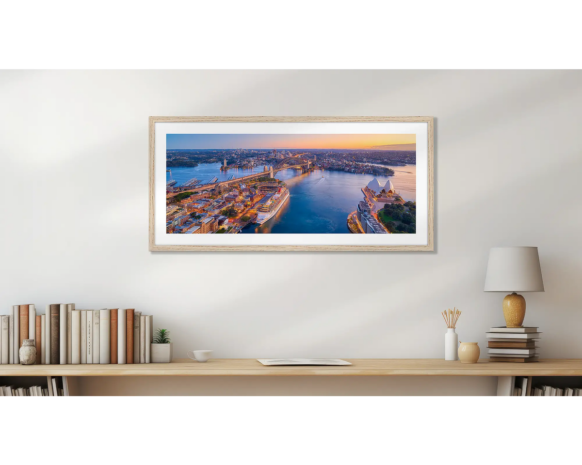 Sydney Awakes. Sunrise over Sydney wall art print, with a timber frame, hung above a bookshelf.