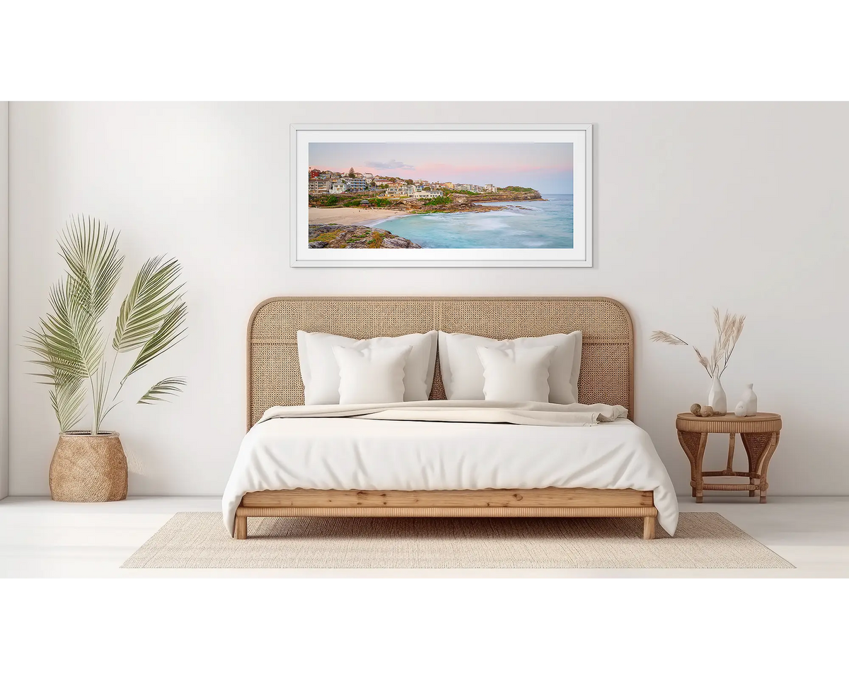 Tama Sundown. Tamara beach sunset artwork, in a white frame, above a bed. 