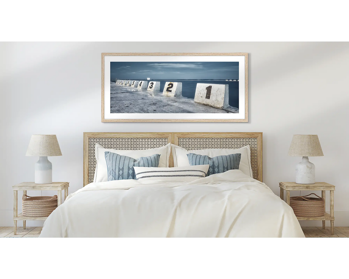 Ten. Merewether baths, Newcastle wall art print, in a timber frame and hung above a bed. 