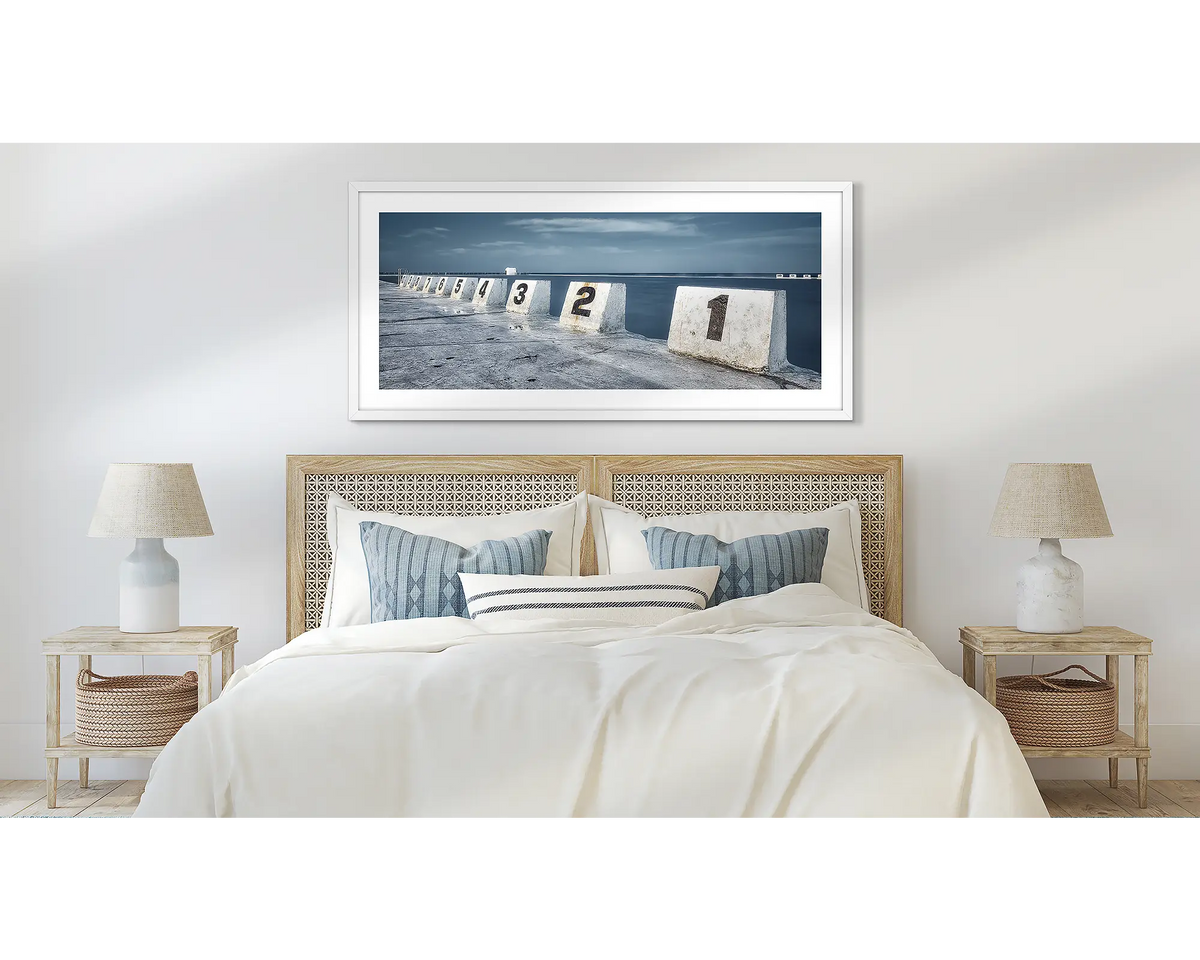 Ten. Merewether baths, Newcastle wall art print, in a white frame and hung above a bed. 