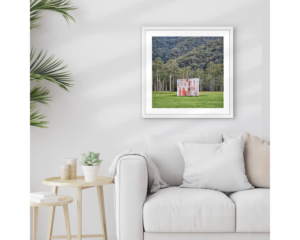 The Box. Framed farm shed wall art print, with a white frame, hung above a couch.