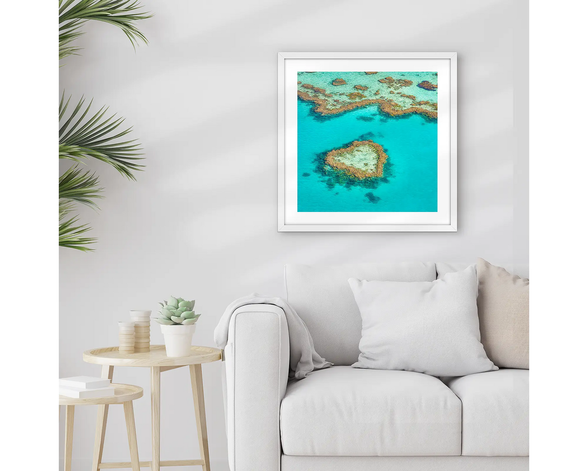 The Heart. Framed Great Barrier Reef wall art print, with a white frame, hung above a couch.