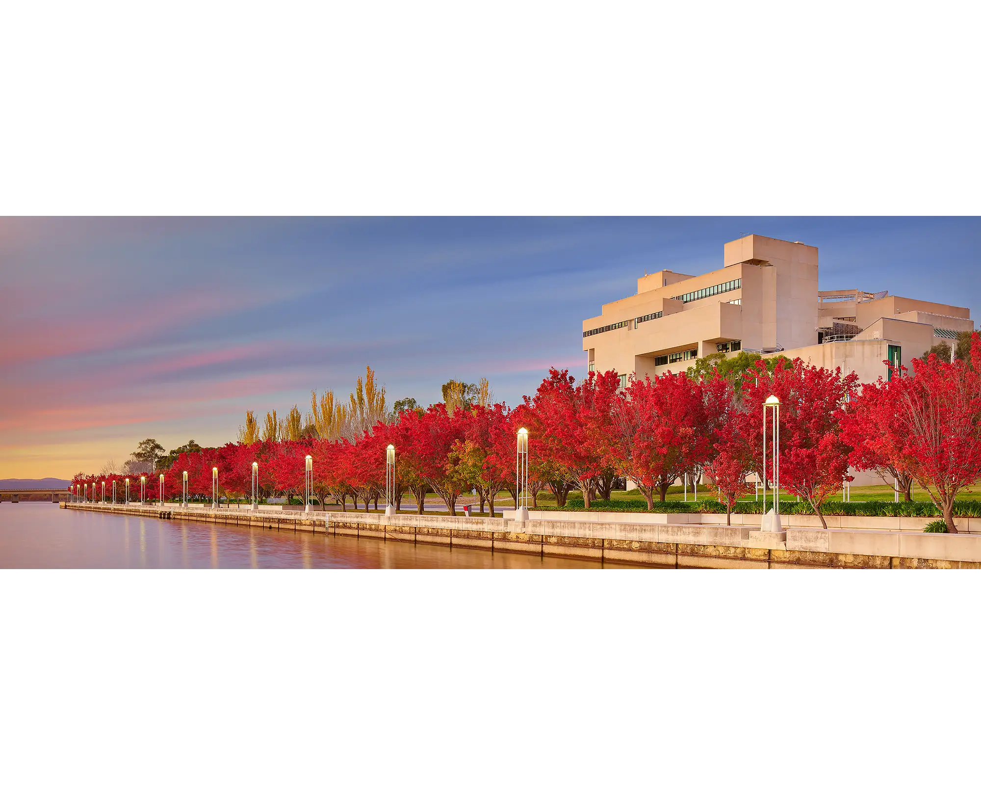 The High Court of Australia photographed at sunrise with Lake Burley Griffin and red trees in the foreground, Canberra, ACT. 