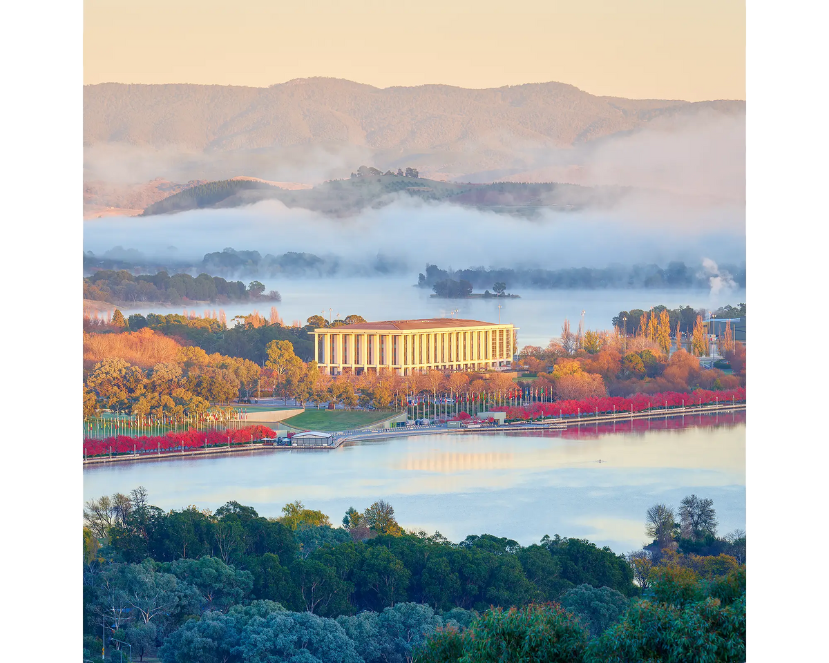 National Library Of Australia at sunrise with fog and red autumn trees, Canberra.