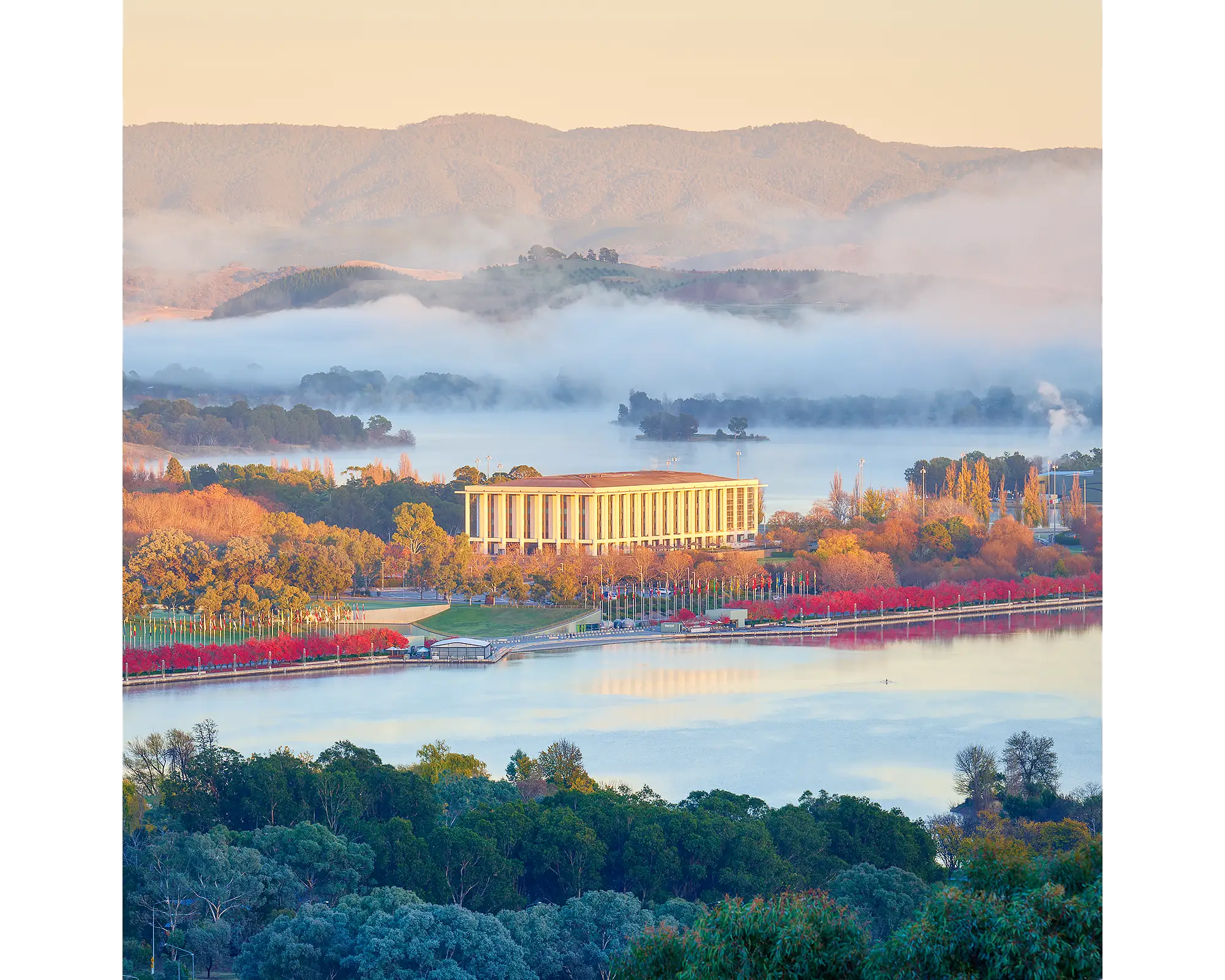 National Library Of Australia at sunrise with fog and red autumn trees, Canberra.