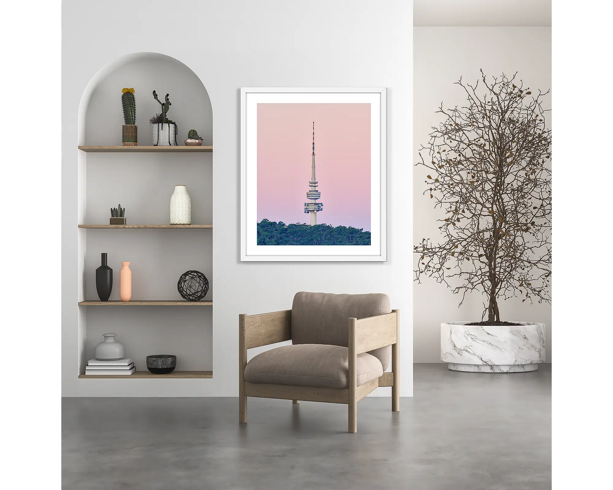 The Needle. Telstra Tower, Canberra wall art print, with a white frame, hung above a chair.