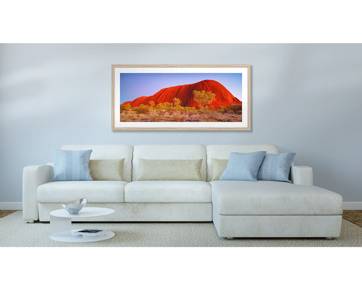 Uluru Awakening. Outback wall art print, with a Tasmanian Oak frame, hung above a couch.