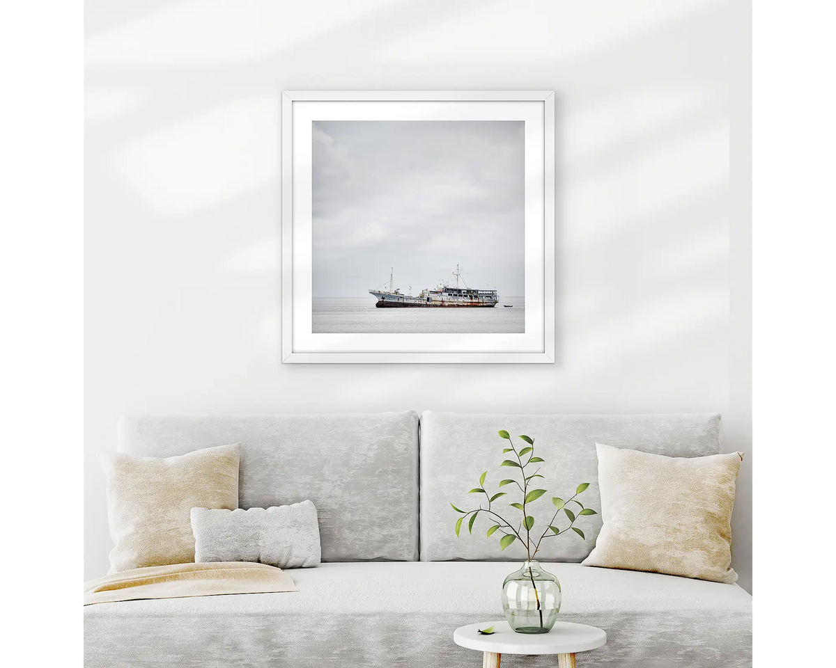 Uncertainty. Old boat wall art print with white frame hung above couch.