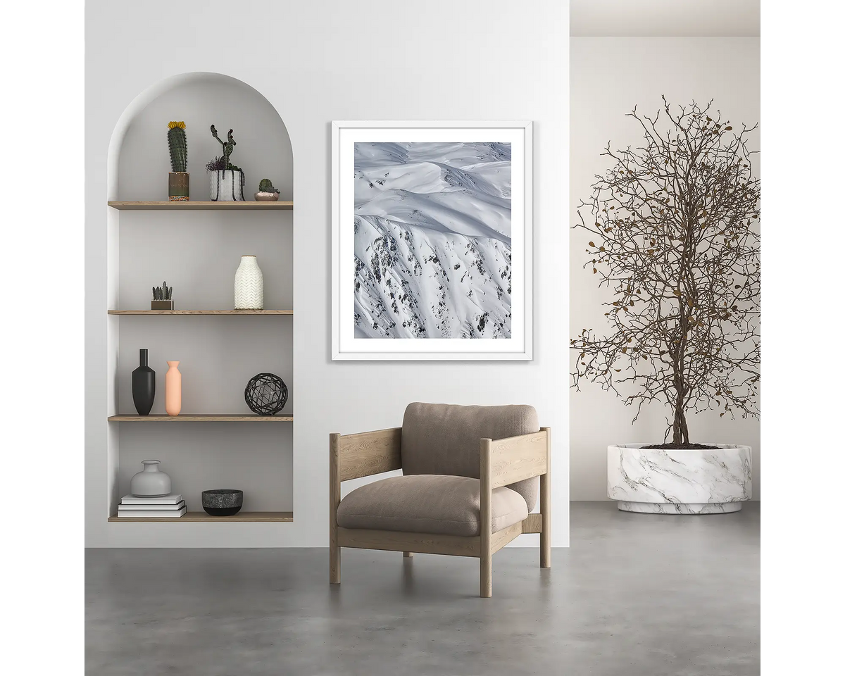 Unveiled. Snow wall art print, with a white frame, hung above a chair.