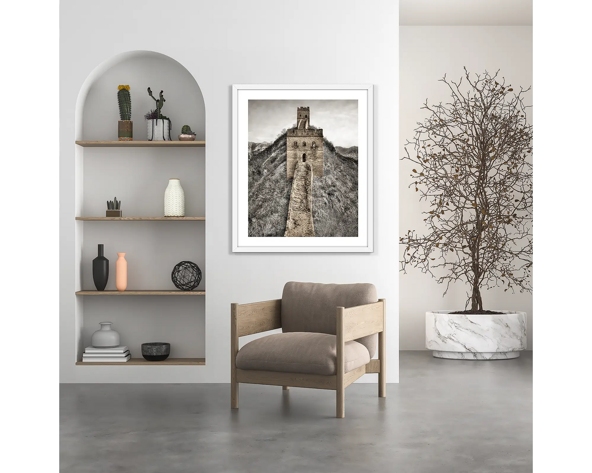 Watchtowers. Great Wall of China wall art print, with a white frame, hung above a chair. 