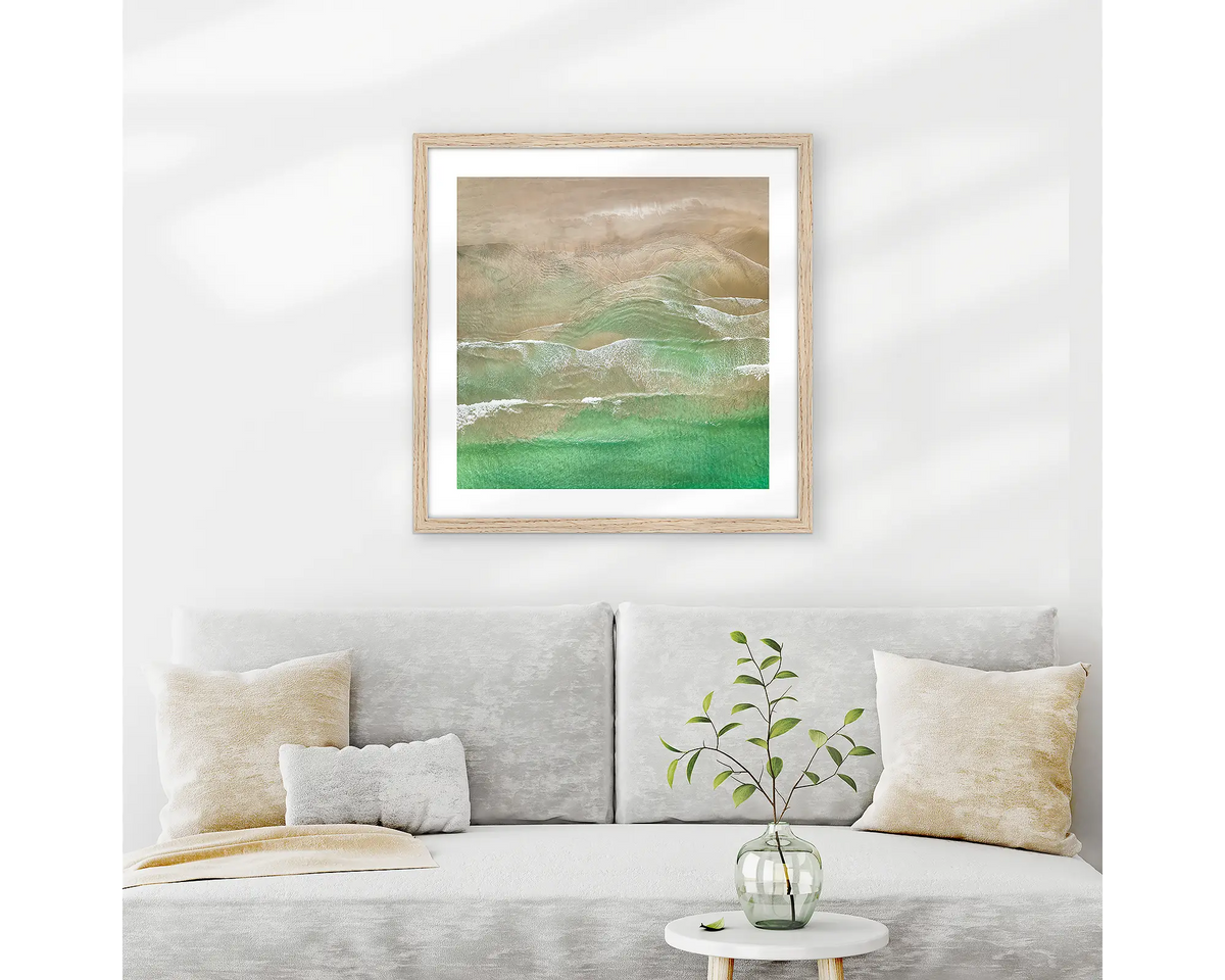 Waveforms. Broulee beach wall art print with timber frame hung above couch.