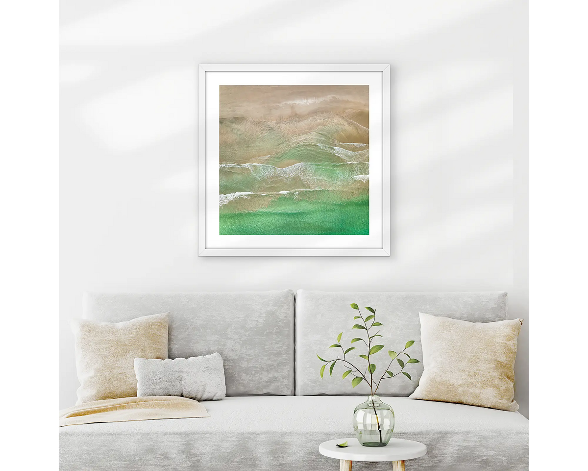 Waveforms. Broulee beach wall art print with white frame hung above couch.