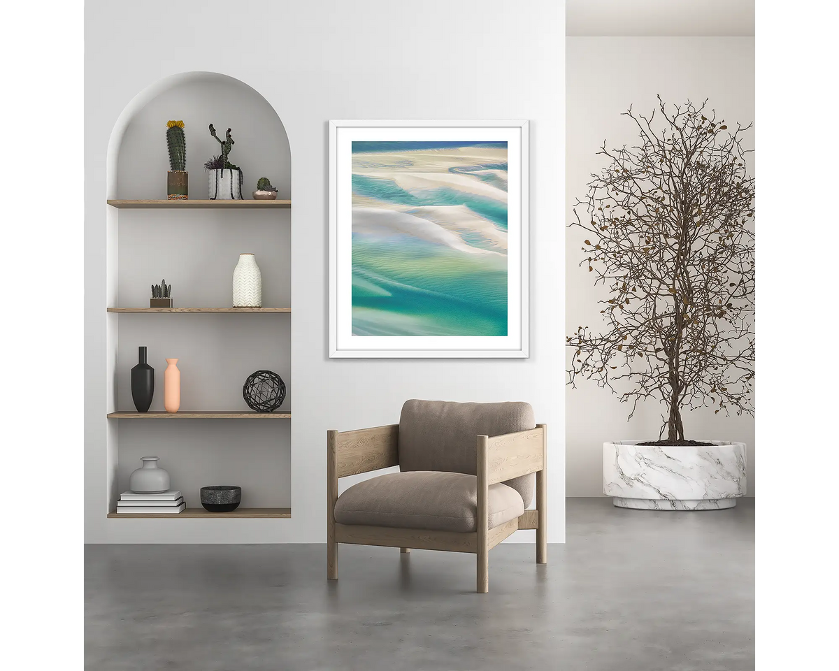 Whitsunday Colours. Coastal wall art print, with a white frame, hung above a chair. 