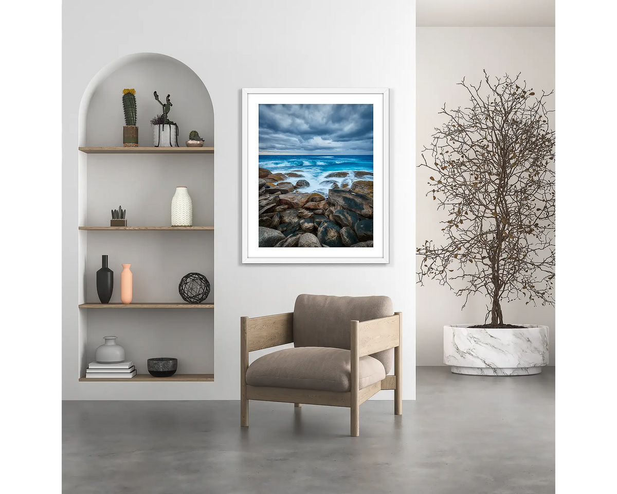 Wild West. Coastal wall art print, with a white frame, hung above a chair. 